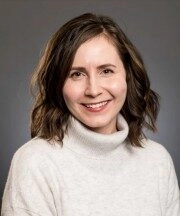 Ariane Gauvreau. White women with brunette hair in a white sweater and smiling.